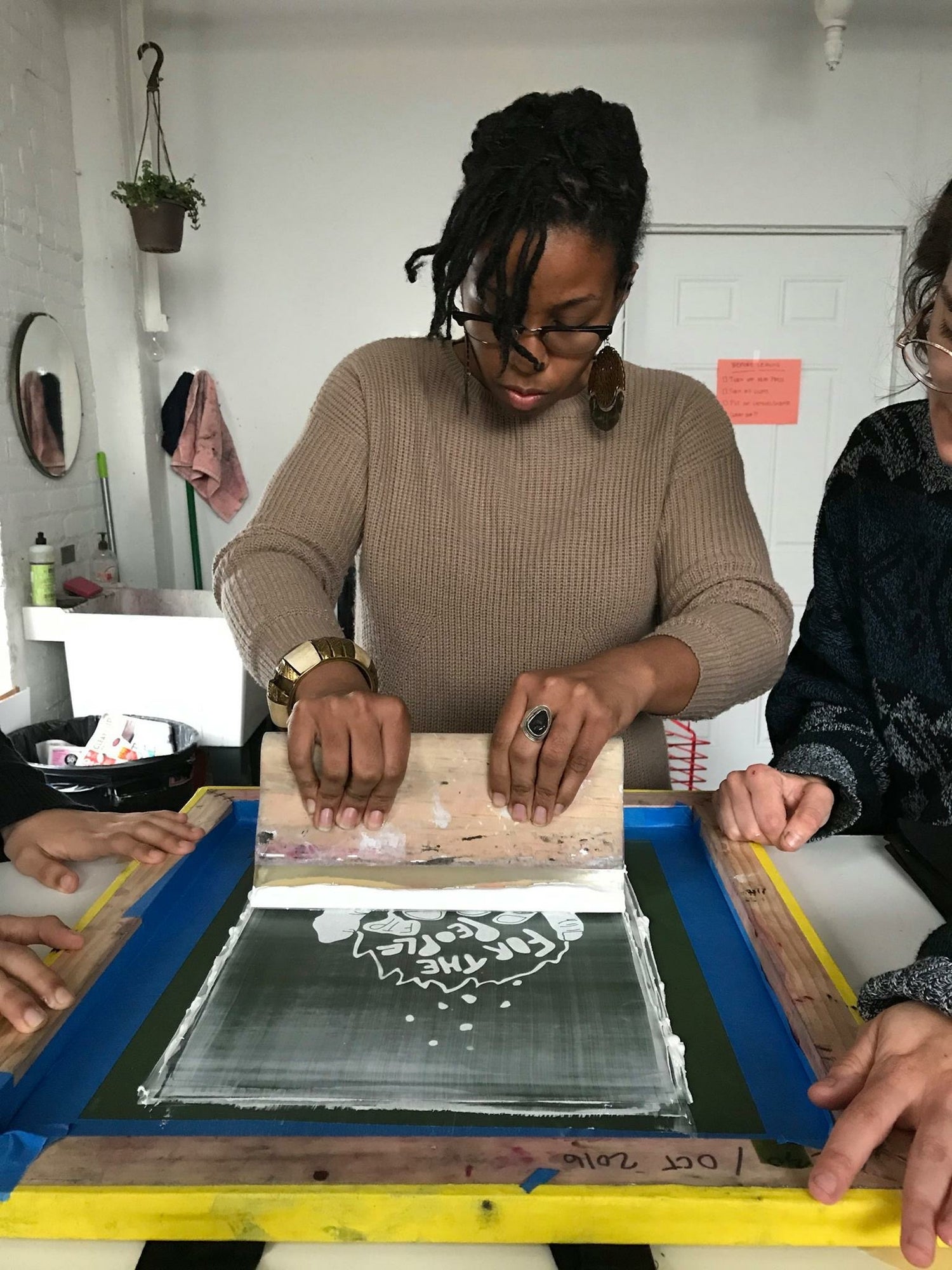 Naimah, a Black woman screen-printing in a studio